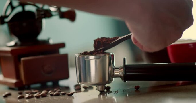 Man pouring ground coffee. View hand from a wooden spoon pours ground coffee into a coffee brewing holder. Home making hot Espresso. Using filter holder. 4K