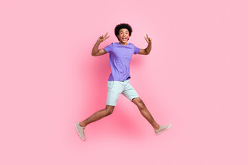 Fototapeta na wymiar Full size photo of impressed crazy ecstatic guy wear t-shirt pants flying showing v-sign run shopping isolated on pink color background