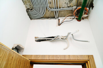 Unfinished electrical wiring on walls and ceiling. Electric cable above the doorway of the interior...