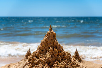 Große Sandburg vor schönem Meer an einem Sandstrand