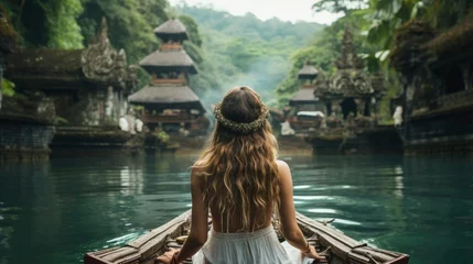 Zelfklevend Fotobehang Woman in beautiful dress relaxing in a wooden boat on a lake in Bali, back view. Enjoying the beautiful scenery on the island of Bali, Indonesia © Neda Asyasi