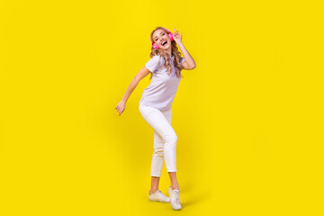 Fototapeta na wymiar Full size photo of good mood positive girl wear violet polo white trousers dancing in headphones isolated on yellow color background