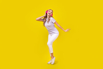 Fototapeta na wymiar Full size photo of lovely nice girl wear violet polo white trousers sing pop song in headphones isolated on yellow color background