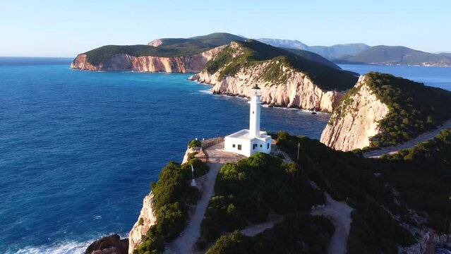 Aerial drone view of the cliffs and the white lighthouse or Cape Ducato Lefkas at sunset in the southern area of Lefkada island. Greece. Rotating pan plane