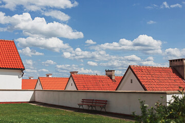 Red tile roofs of camaldolese monks' houses against cloudy sky. Wigry village, Poland.