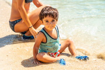 Mother and son enjoying the summer on the beach in summer of Paralia Mikros Gialos in the south of the island of Lefkada. Greece.