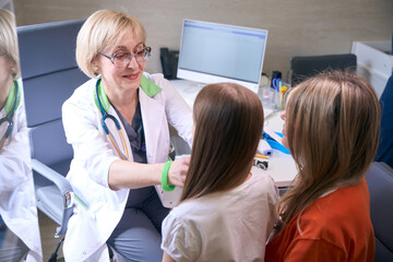 Woman pediatrician examines a girl at reception in pediatric office