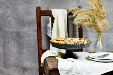 Homemade custard tart with almond flakes on old table with old chair, dark food photography