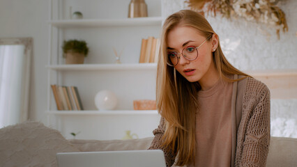 Caucasian shocked woman in glasses looking at laptop reading bad news close mouth with hands holding head with shock failure student girl lost with computer businesswoman worry about business problem