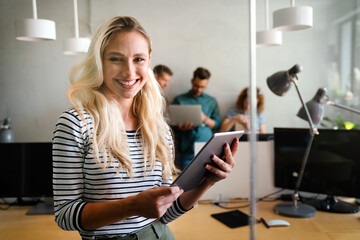 Smiling confident business leader looking at camera and standing in an office at team meeting.