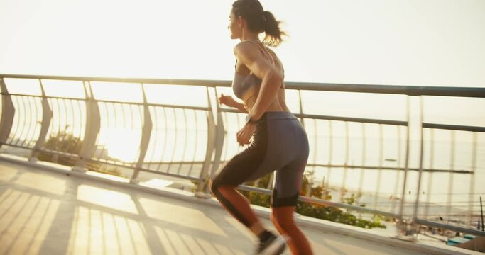 A sports girl in a sports summer uniform starts her run from a low start in the morning. Jogging at Sunrise