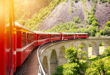 Red train moving on vaiduct in summer in Switzerland