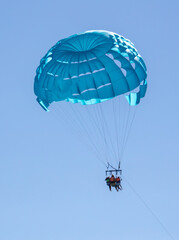 A blue parachute flies over the sea