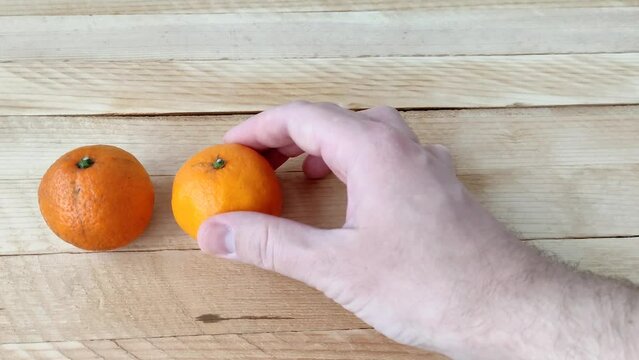 Man puts tangerines in the row on a wooden background