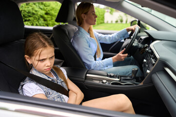 Upset girl is driving with her mother in a car