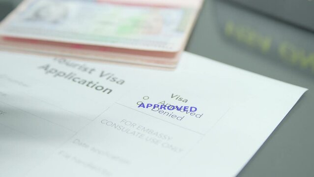 Close up putting stamp approved into visa application paper 