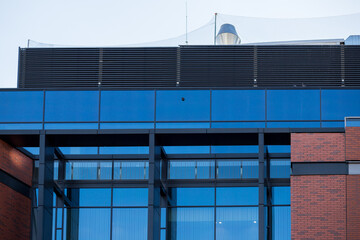 Glass building in Poland with dark blue windows. Exhaust hood of a building made of glass. Modern design of the facade of the shopping center. Financing the construction of a shopping center.