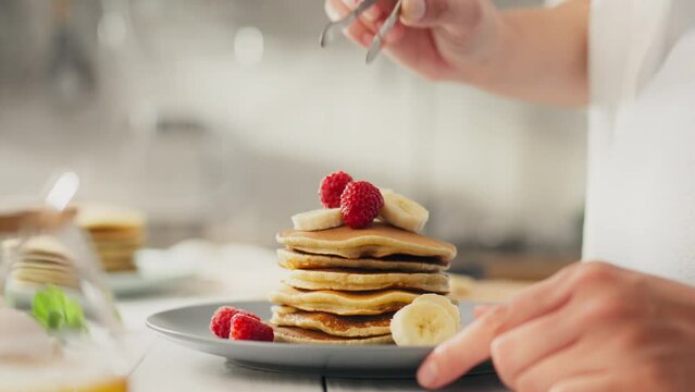 Pancakes, a young woman prepares desserts and sweet treats, in the kitchen of a private home. a white woman is preparing pancakes for breakfast, applying a new mix of different fruits and berries