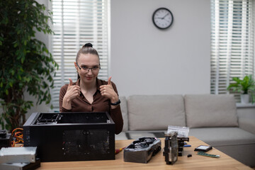 Dziewczyna naprawiająca komputer unosi dwa kciuki do góry. - obrazy, fototapety, plakaty