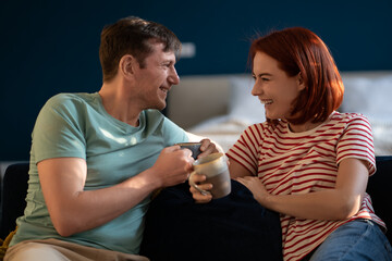 Husband and wife communicate, drink coffee. Romantic couple happily laughing, smiling, having fun, enjoying each other company, getting closer. Cheerful joyful conversations, friendly chat talk