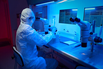 Embryologist in protective uniform performs ICSI procedure