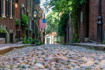 Boston, MA, USA-August 2022; Frog’s eye view down the cobblestones of Acorn Street that is lined...