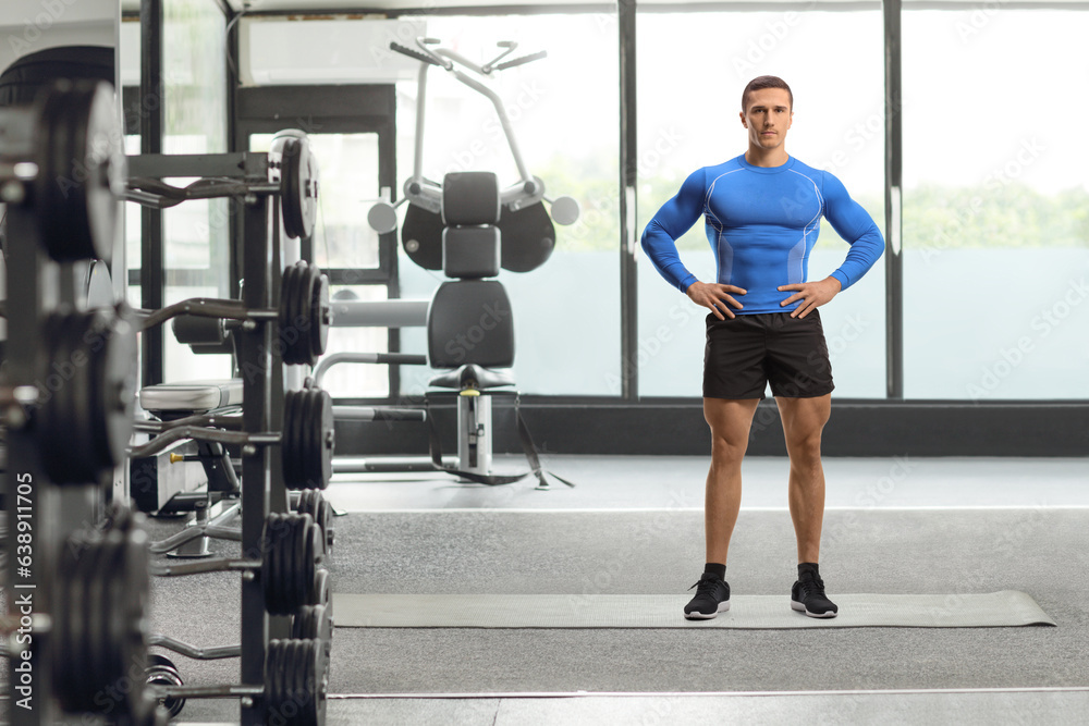 Wall mural Full length portrait of a bodybuilder posing at a gym