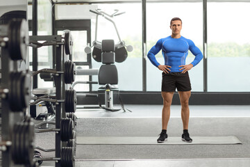 Full length portrait of a bodybuilder posing at a gym