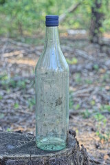 one old dirty white glass bottle stands on gray stump on the street 
