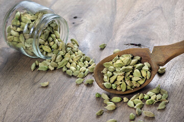 green cardamom pods in a wooden spoon on a wooden table