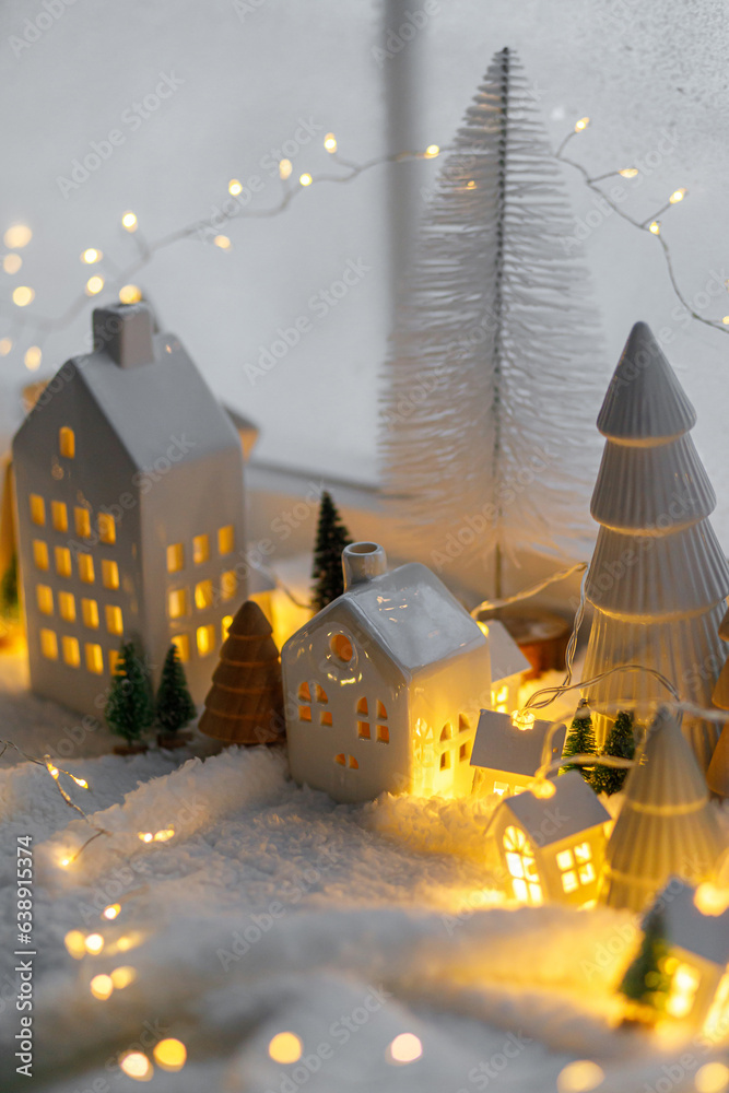 Wall mural cozy christmas miniature village. stylish little ceramic houses and wooden trees on soft snow blanke