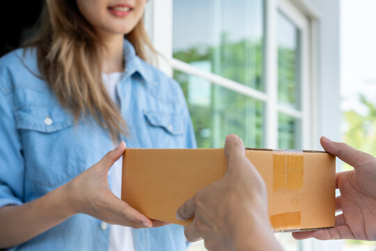 Happy smiling woman receives boxes parcel from courier in front house. Delivery man send deliver express. online shopping, paper containers, takeaway, postman, delivery service, packages