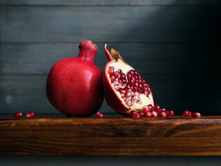 Image of Still Life with Pomegranate. Dark wood background, antique wooden table.