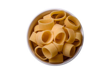 Raw uncooked pasta in a white ceramic bowl with spices and herbs