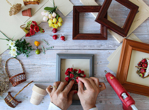 Woman crafting making handmade framed baskets with tiny fruits and flowers arrangements to be sold or for gifts. 