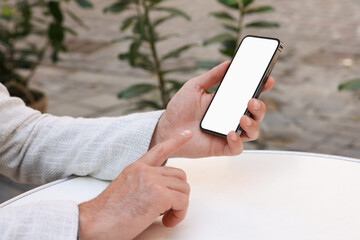 Man using smartphone at white table outdoors, closeup