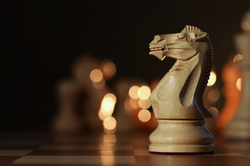 Wooden knight on chessboard, selective focus. Space for text