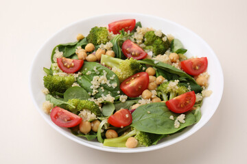 Healthy meal. Tasty salad with quinoa, chickpeas and vegetables on beige table, closeup