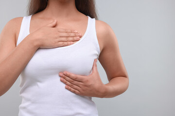 Woman doing breast self-examination on light grey background, closeup