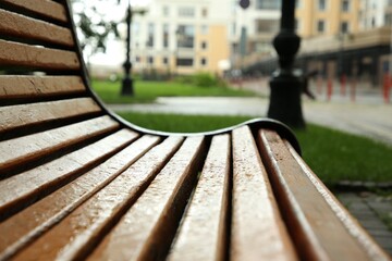 Wooden bench with water drops outdoors, closeup. Rainy weather