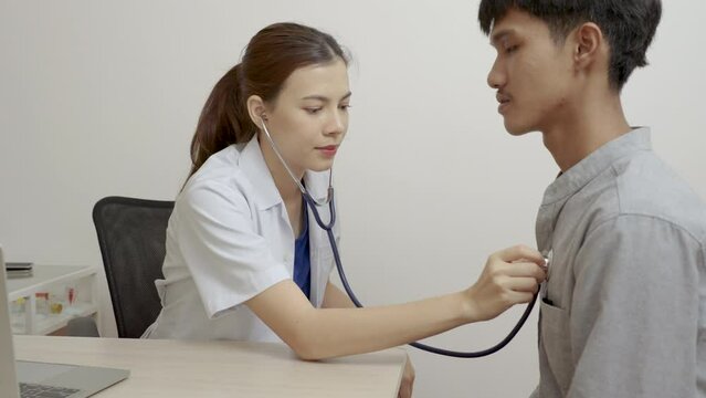 Beautiful female doctor uses stethoscope to listen to male lung function.
