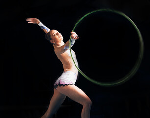 Portrait, training with a gymnastics hoop and a woman in the gym for a performance showcase or practice. Fitness, dance and concert with a female athlete on a dark background for routine or recital