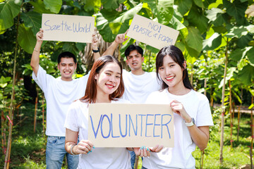 Group of young Asian volunteers holding paper banners Help campaign to save the environment. save...