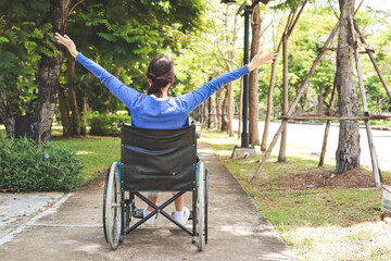 Asian woman sitting in a wheelchair taking a walk in the park Feel positive and motivated. Living to be happy, enjoy life outdoors.