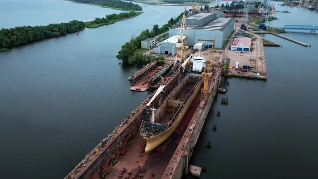 Workers are repairing a ship in a dry dock. The shipyard is building a ship. A large vessel in stock at the shipyard. 4k footage
