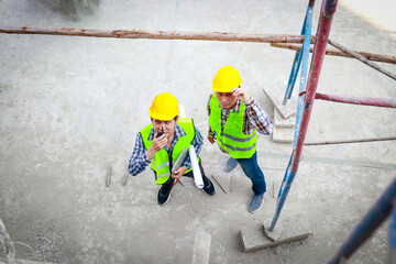 Top view of contractor holding walkie talkie to work with subordinates on construction site. industry concept construction technology