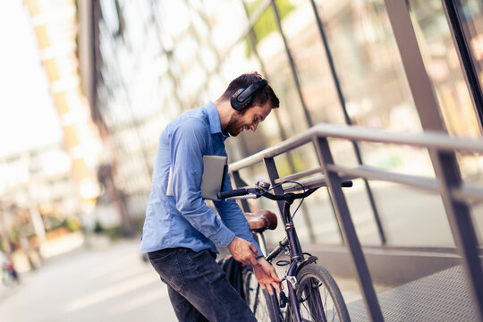 Businessman on bicycle using hands free listening for music. Business, work, and people concepts.