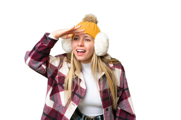 Young pretty blonde woman wearing winter muffs over isolated chroma key background looking far away with hand to look something