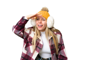 Young pretty blonde woman wearing winter muffs over isolated chroma key background looking far away with hand to look something