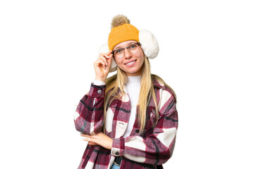 Young pretty blonde woman wearing winter muffs over isolated chroma key background with glasses and happy